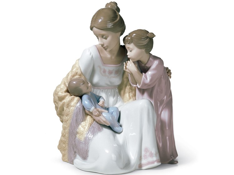 Porcelain figurine of a mother and her daughter looking tenderly at their little brother.