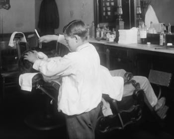 A barber in action with a straight razor in the early 1900s