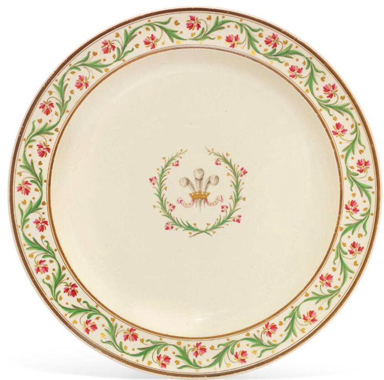 A plate with gold rims and green and pink flowers