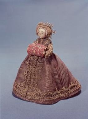 Doll dressed in an elaborate gown, wearing a headgear